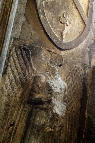 Wall relief of a headless angel with clover overhead